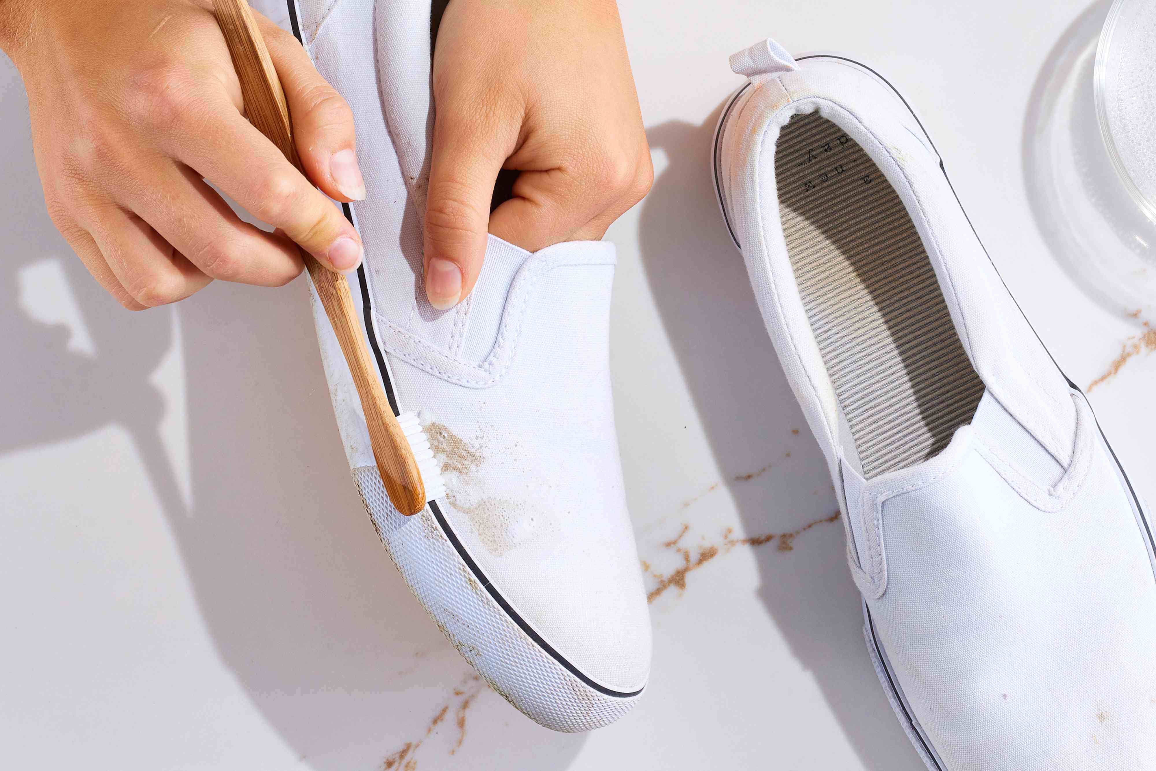 A person carefully cleaning white sneakers